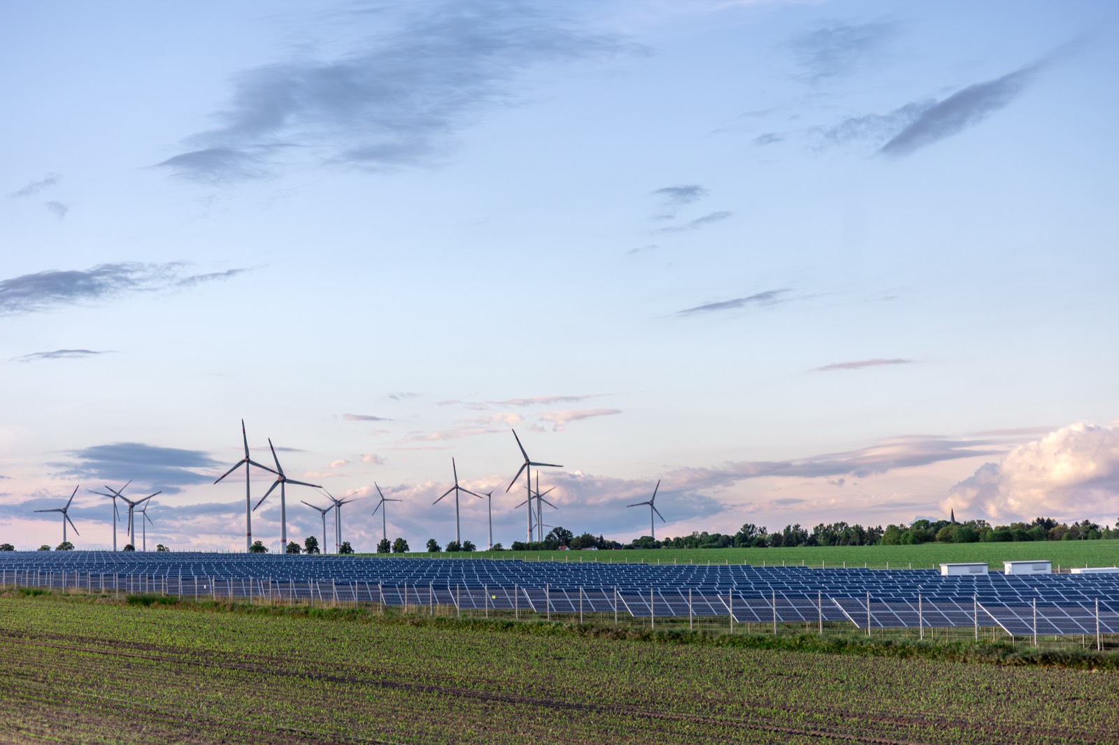 Solar panels with wind turbines on the horizon